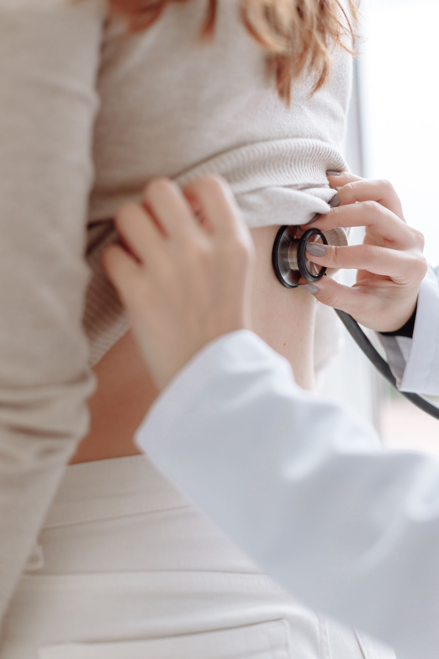 Clinician auscultating a patient's back with a stethoscope