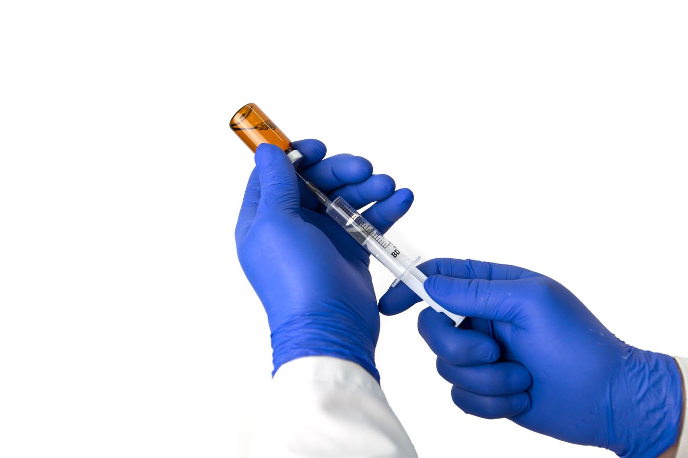Gloved hands drawing medication from a vial