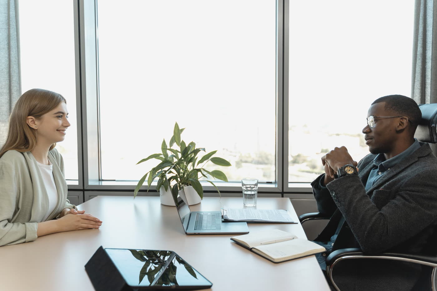 A job candidate smiling across a desk at a hiring manager during an interview in a bright office