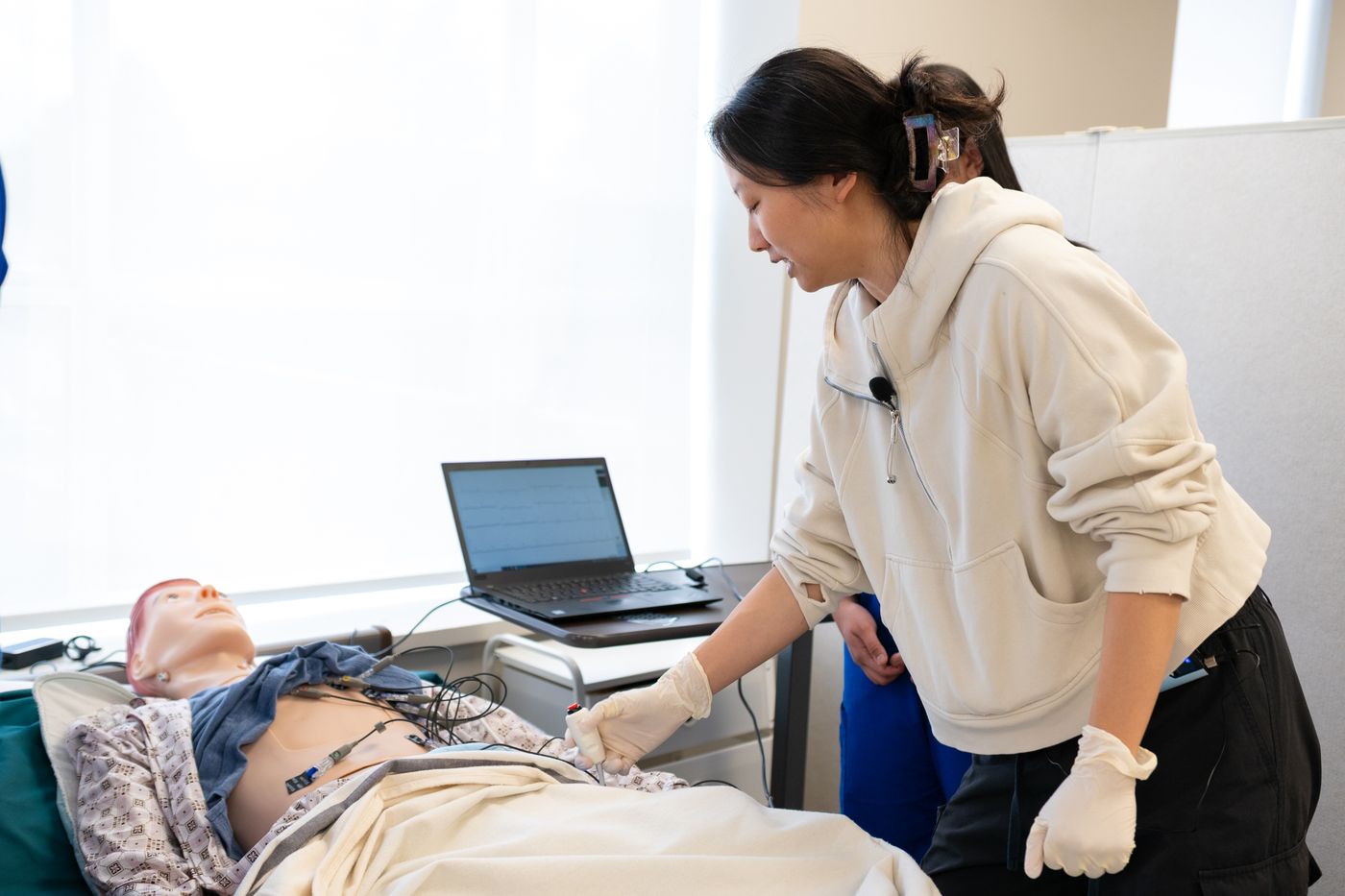 Nursing student working with a simulation mannequin connected to monitoring equipment