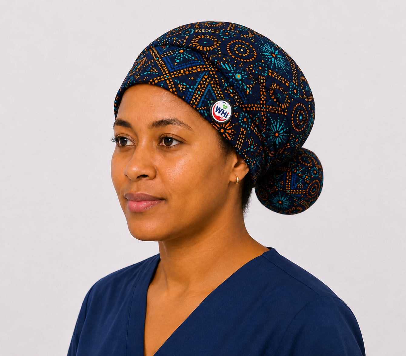 Wahero bouffant scrub cap in a navy, teal and orange African print, worn with the WHi pin